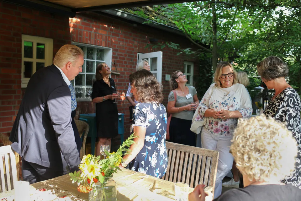 Veranstaltungsgäste im Gespräch zwischen Sitzgruppen auf der Terrasse.